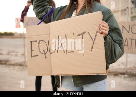 Eine Gruppe von Demonstranten auf der Straße mit einem Schild, auf dem die Gleichberechtigung steht. Aktivistin, die Frauenmacht demonstriert. Stockfoto