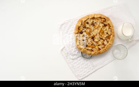 Gebackener runder Kuchen mit Apfelstücken, bestreut mit Mandelflocken auf einem weißen Tisch, Draufsicht Stockfoto