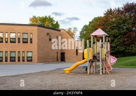 Schulgebäude und Schulhof mit Spielplatz ohne Kinder in Kanada. Stockfoto