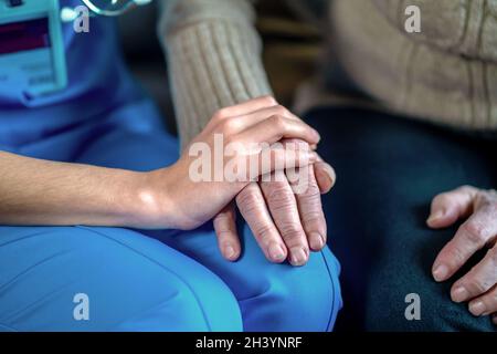 Die Hände der jungen Frau halten die Hände der Großmutter, eine ältere Patientin. Stockfoto