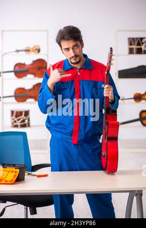 Junger männlicher Mechaniker, der am Arbeitsplatz Musikinstrumente repariert Stockfoto