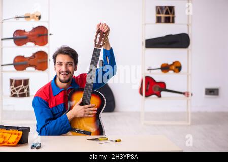 Junger männlicher Mechaniker, der am Arbeitsplatz Musikinstrumente repariert Stockfoto