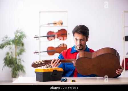 Junger männlicher Mechaniker, der am Arbeitsplatz Musikinstrumente repariert Stockfoto