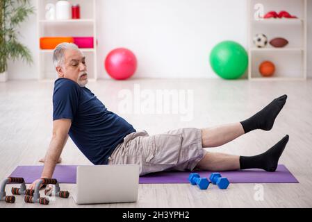 Alter Mann, der drinnen Sportübungen macht Stockfoto