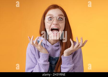 Schockiert aufgeregt überwältigt junge schreiende glücklich Rotschopf Mädchen mit Brille gewinnen hören ausgezeichnete Nachrichten laut rejo rufen Stockfoto