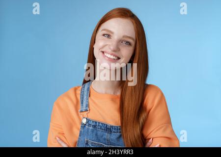 Charismatische freundlich angenehm rothaarige Mädchen blaue Augen lächelnd freundlich zuhören höflich Kunde stehend blauen Hintergrund kippenden Kopf Stockfoto