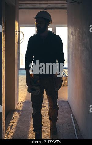 Ein Baumeister in Arbeitskleidung mit Schutzhelm auf einer Baustelle. Stockfoto