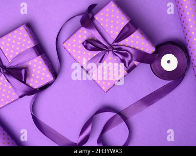 Lila Geschenkbox in Seidenband auf einem violetten Hintergrund verpackt Stockfoto