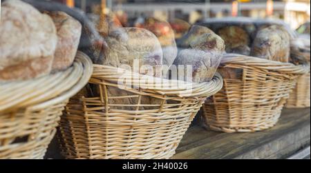 Backstube mit Vitresen voll mit leckerem Brot in Korbkörben. Gesundes natürliches Roggen- und Vollkornbrot in der örtlichen Bäckerei. St Stockfoto