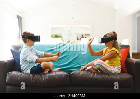 Kaukasischer Bruder und Schwester sitzen auf der Couch und benutzen vr-Headsets im Wohnzimmer Stockfoto