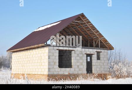 Bau eines Hauses mit einem Metalldach, Traversen, Sparren im Winter. Stockfoto