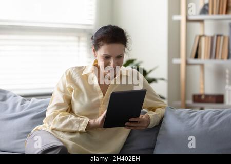 Entspannt lächelnde ältere Frau im Ruhestand mit Tablet. Stockfoto