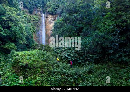 Luftaufnahme von Mutter und Sohn, die am Wasserfall Cascata da Ribeira Quente, Sao Miguel Island, Azoren, Portugal, mit Drohne spazieren gehen Stockfoto