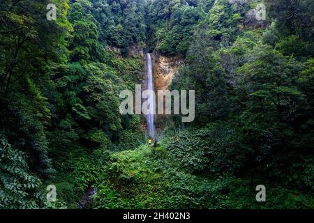Luftaufnahme von Mutter und Sohn, die am Wasserfall Cascata da Ribeira Quente, Sao Miguel Island, Azoren, Portugal, mit Drohne spazieren gehen Stockfoto