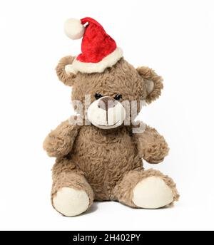 Niedlicher brauner Teddybär sitzt in roter weihnachtsmütze auf weißem Hintergrund Stockfoto