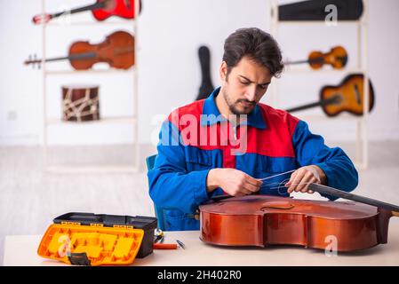 Junger männlicher Mechaniker, der am Arbeitsplatz Musikinstrumente repariert Stockfoto