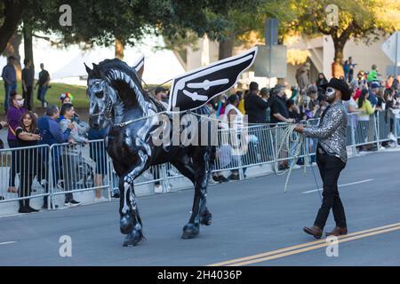 Houston, USA. Oktober 2021. Ein Mann geht mit einem Pferd während der Parade von Dia de los Muertos in Dallas, Texas, USA, am 30. Oktober 2021. Dia de los Muertos, bekannt als Tag der Toten, ist ein bekannter traditioneller mexikanischer Feiertag zum Gedenken an verstorbene Geliebte. Quelle: Dan Tian/Xinhua/Alamy Live News Stockfoto