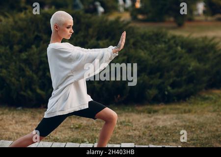 Millennial junge Frau blond kurze Haare im Freien tun Qigong Stockfoto