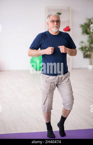 Alter Mann, der drinnen Sportübungen macht Stockfoto