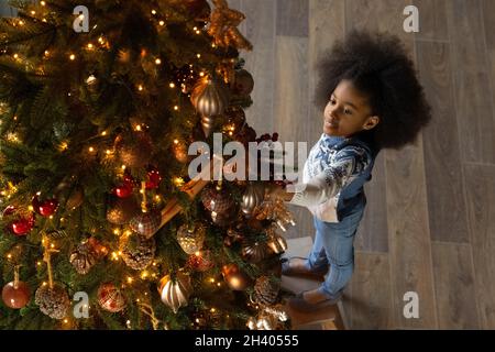 Kleine biracial Mädchen schmücken Weihnachtsbaum zu Hause Stockfoto