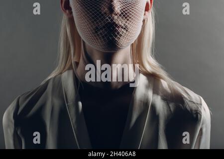 Nahaufnahme Porträt von weißen kaukasischen Albino blonde Frau Mode-Modell trägt Quarantäne medizinische Gesichtsmaske grobes Netz auf gre Stockfoto