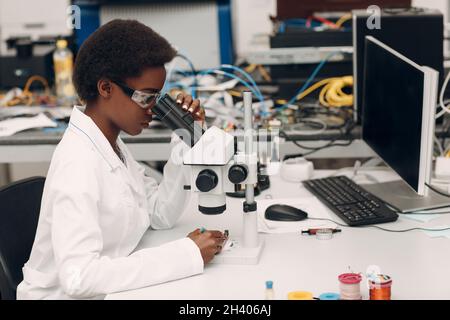 Wissenschaftlerin afroamerikanische Frau, die im Labor mit elektronischen Instrumenten arbeitet Stockfoto