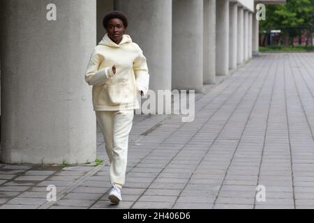 Afroamerikanische Läuferin Frau im Hoodie beim Joggen im Freien Stockfoto