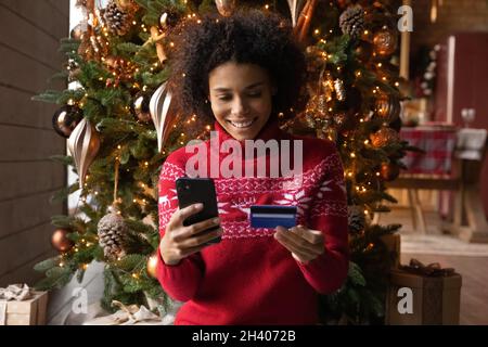 Glückliche Biracial Frau Shop online mit Smartphone Stockfoto