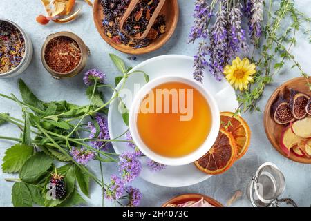 Tee. Kräuter, Blumen und Früchte um eine Tasse Tee herum lag eine flache Decke Stockfoto