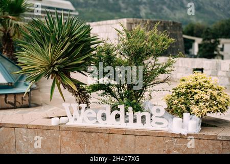 Weiße Holzbeschriftung HOCHZEIT mit Kerzen außen. Stockfoto