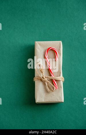 Bastelpapier-Umschläge mit Schnur gebunden und mit Weihnachtsbonbons verziert. Umschläge aus Kraft-Grünpapier und Süßigkeiten. Stockfoto