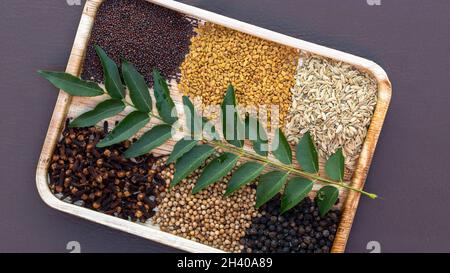 Pfeffer, Koriander, Fenchel, Nelken, Bockshornklee, Kreuzkümmelkerne mit dem Laubblatt auf der Palmtellerplatte aus der Nähe von oben Stockfoto