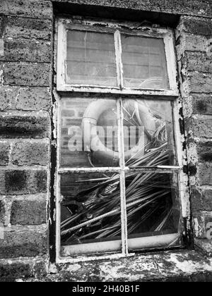 Eine vertikale Graustufenaufnahme eines Fensters auf dem alten Steingebäude Stockfoto