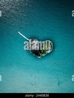 Eine Luftaufnahme eines Bootes, das eine herzförmige Insel durchbricht Stockfoto