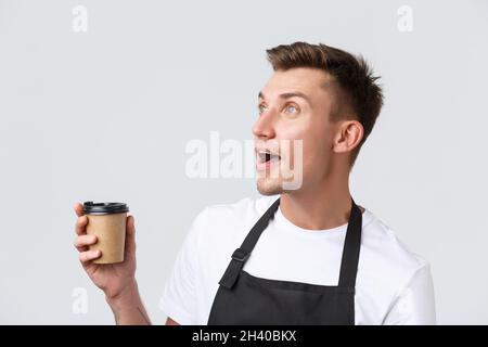 Cafe und Restaurants, Coffee Shop Besitzer und Retail-Konzept. Nahaufnahme eines überraschten und verblüfften blonden Verkäufers, Barista, der nach oben schaute Stockfoto