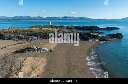 Blick auf die Insel Llanddwyn mit dem Leuchtturm von Twr Bach und den Snowdonia-Bergen im Hintergrund, Anglesey, North Wales, Großbritannien. Aufgenommen am 15. Oktober 2021. Stockfoto