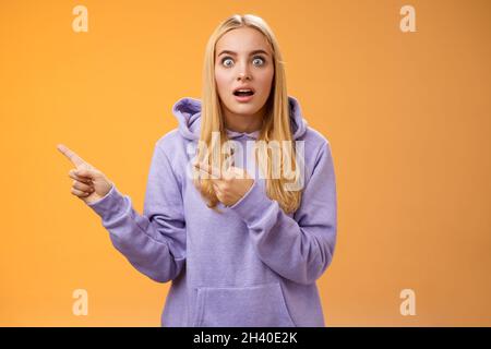 Wow erstaunt beeindruckt gut aussehende blonde europäische Frau in Kapuzenpullover Augen wunderte überrascht gefragt Tropfen Kiefer zeigt l Stockfoto