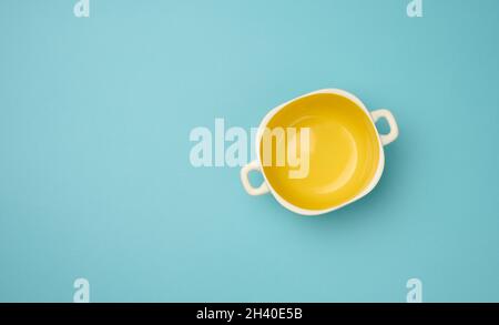 Leere gelbe Suppenteller auf blauem Hintergrund, Draufsicht Stockfoto