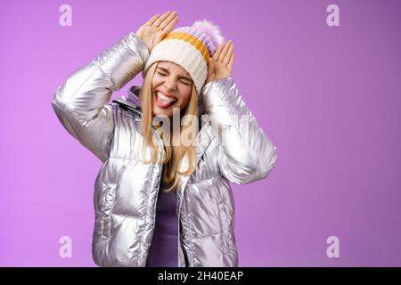 Sorglos lustig amüsiert blonde kaukasische Mädchen 25s mit Spaß spielen um imitieren Hase enge Augen zeigen Zunge aufgeregt ma Stockfoto