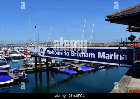 Ein Blick auf die Menschen, die die Brücke der Brixham Marina überqueren, in den geschäftigen und geschäftigen Yachthafen, wo zahlreiche Boote und Sportboote sicher vertäut sind. Stockfoto