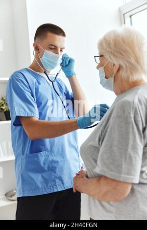 Arzt in medizinischer Maske hört auf die Gesundheitsversorgung des Patienten Stockfoto