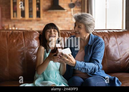 Aufgeregt Enkelin Mädchen erhalten Geburtstagsgeschenk von glücklichen Oma Stockfoto