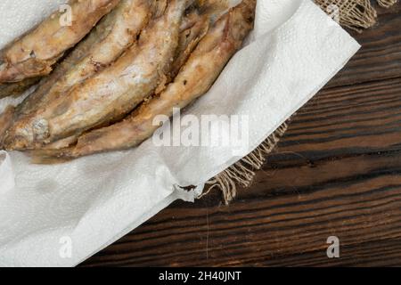 Gebratener Fisch auf einer Papierserviette in einem Korbkorb auf einem Holztisch Stockfoto