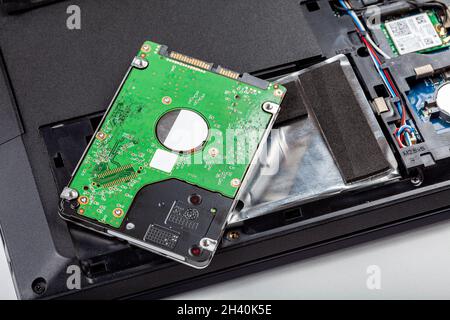 Eine neue 2.5-Zoll-Festplatte, die auf einem modernen, zerlegten, geöffneten Laptop liegt, Dateispeicher. Festplattenaustausch, Schutz digitaler Daten Stockfoto