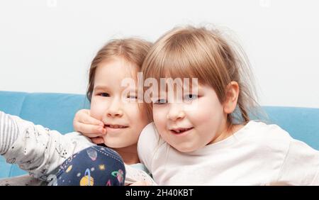 Zwei junge Kinder im Grundschulalter, Schwestern, Geschwister, Kinder, die sich zu Hause lächelnd herumtollten, witziges, schrulliges Porträt, Nahaufnahme des Gesichts. Humor, Stockfoto