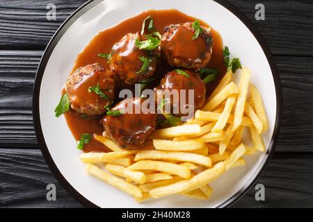 Boulets a la Liegeoise ein klassischer belgischer Fleischball in Apfelsauce und Pommes Frites in der Nähe auf dem Teller auf dem Tisch. Horizontale Draufsicht von oben Stockfoto