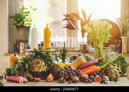 Verschiedene Lebensmittel im Hintergrund des Fensters: Trauben, Karotten, Artischocke, Avocado, Feigen und Kürbisse. Nachhaltiger Lebensstil mit unverpacktem, gesundem Gemüse Stockfoto
