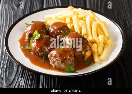 Belgische Boulets Sauce Lapin Fleischbällchen in Apfelsoße und Pommes Frites in der Nähe auf dem Teller auf dem Tisch. Horizontal Stockfoto