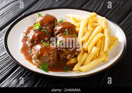 Belgische Fleischbällchen-Boulets eine La Liegeoise in Apfelmus und Pommes Frites in der Nähe auf dem Teller auf dem Tisch. Horizontal Stockfoto