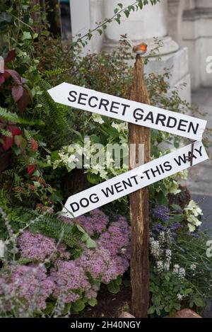 schild, das die Leute in den geheimen Garten führte und Hund ging diesen Weg Stockfoto